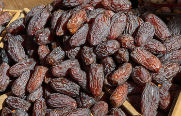 Close-up of a pile of dried dates in natural light, showcasing their rich color and wrinkled texture. Healthy and traditional snack often used in Middle Eastern cuisine.