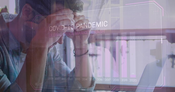 Image of covid 19 data processing and statistics over worried caucasian man using laptop