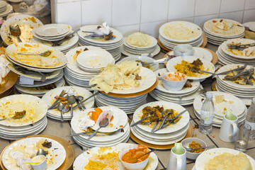 Pile of dirty plates and cutlery chaos with leftovers on the Kitchen Table