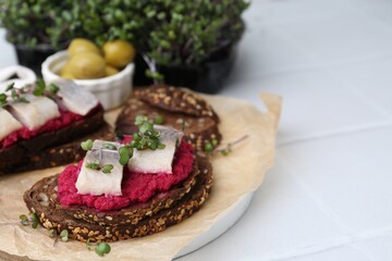 Tasty sandwiches with herring and horseradish sauce on white table, closeup. Space for text