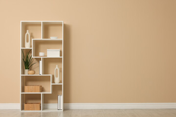 Shelving unit with decor near beige wall indoors. Space for text
