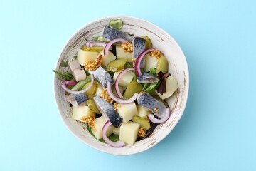 Delicious salad with herring, vegetables and mustard on light blue background, top view