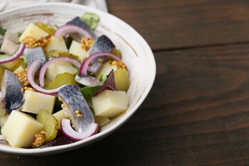 Delicious salad with herring, vegetables and mustard in bowl on wooden table, closeup. Space for text