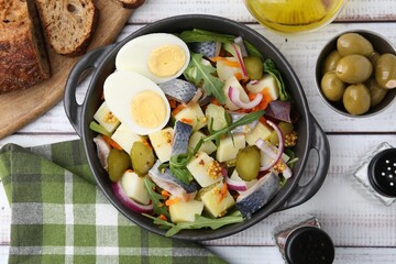 Delicious salad with herring, egg and vegetables served on white wooden table, flat lay