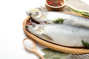 Salted herrings and spices on white wooden table, closeup. Space for text