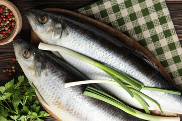 Salted herrings and spices on wooden table, flat lay