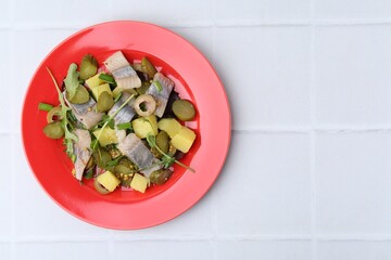 Delicious salad with herring on white tiled table, top view. Space for text