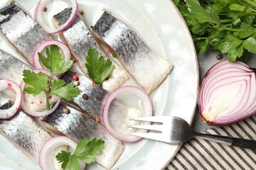 Pieces of delicious herring with spices and onions served on table, closeup