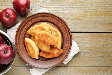 Delicious fried pyrizhky (stuffed pies) with apples on wooden table, flat lay. Space for text