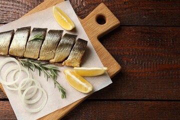 Smoked herring, onion, rosemary and lemon on wooden table, top view. Space for text
