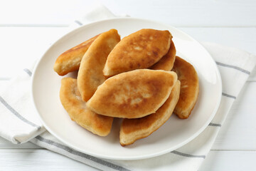 Delicious fried pyrizhky (stuffed pies) on white wooden table, closeup