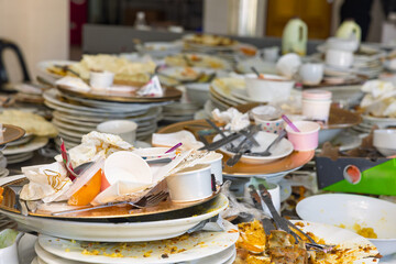 Pile of dirty plates and cutlery chaos with leftovers on the Kitchen Table