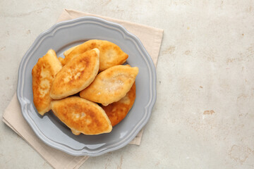 Delicious fried pyrizhky (stuffed pies) on light grey table, top view. Space for text