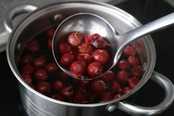 Making compot of cherries. Simmering fruits in pot on stove, closeup