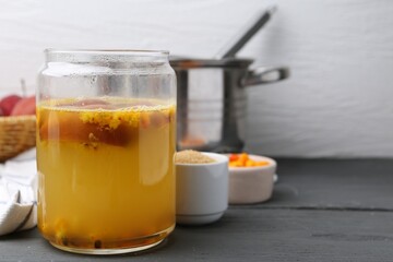 Tasty compot in glass jar and ingredients on grey wooden table, closeup. Space for text