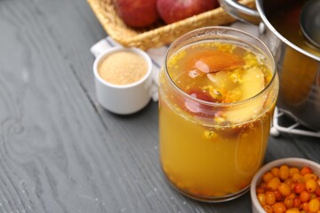 Tasty compot in glass jar and ingredients on grey wooden table, closeup. Space for text