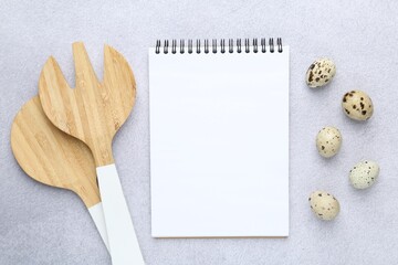 Blank recipe book, quail eggs and utensils on light table, top view. Mockup for design