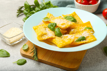 Delicious ravioli with cheese and basil served on grey table, closeup