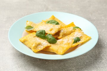Delicious ravioli with cheese and basil on grey table, closeup