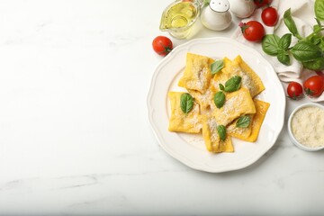 Delicious ravioli with cheese and basil served on white marble table, flat lay. Space for text