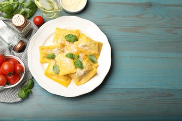 Delicious ravioli with cheese and basil served on light blue wooden table, flat lay. Space for text