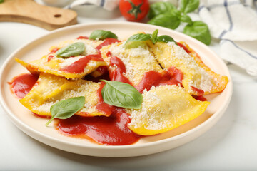 Delicious ravioli with tomato sauce, parmesan cheese and basil on white table, closeup