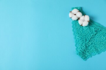 Women's underwear. Beautiful turquoise panties and cotton flowers on light blue background, top view. Space for text