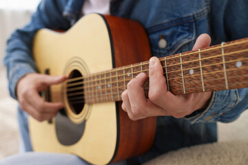 Obraz premium Man playing guitar on armchair indoors, closeup