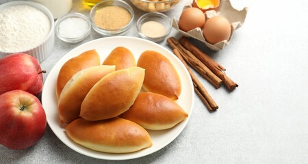 Tasty baked patties and ingredients on light grey table, closeup. Space for text
