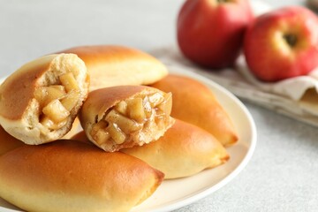 Tasty baked patties with apples on light grey table, closeup