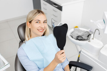 Smiling patient sitting in dentist chair showing perfect teeth