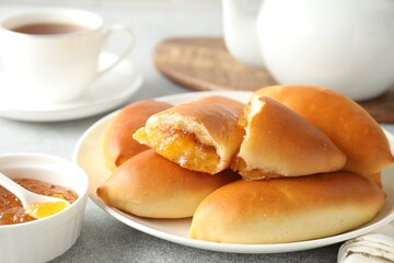 Tasty baked patties with orange jam on light grey table, closeup