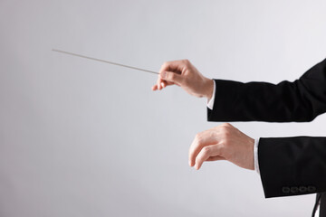 Professional conductor with baton on light grey background, closeup. Space for text