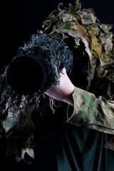 A person wearing camouflage clothing is holding a camera