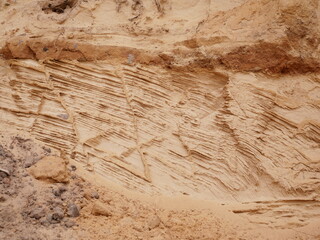 The cliff face displays fascinating layered patterns created by fresh erosion. Wave-like structures...