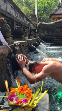 Close-up of man performing traditional water purification ritual at Tirta Empul Temple in Ubud Bali, Indonesia. Spiritual moment ideal for religion, culture, and travel content.