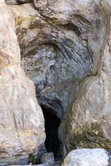 a cave in a rock, an old rock with a hole in it