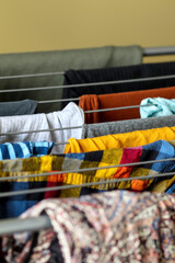 Yellow clothes drying on a metal folding rack, close-up shot with a clean background, vertical...