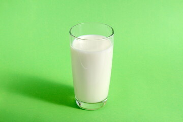 There is a glass of milk on a green background.	