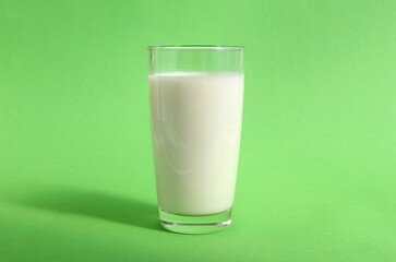 There is a glass of milk on a green background.	