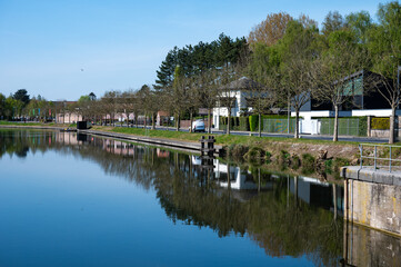 Obraz premium Boats and houses reflecting in the water of the river Lys or Leie in Menen, West Flanders, Belgium