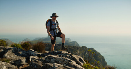 Hiking, travel and relax with man in nature for fitness, mountain adventure and thinking. Space, rock and mindfulness with person outdoor view on cliff for trekking holiday, tourism explore and peace