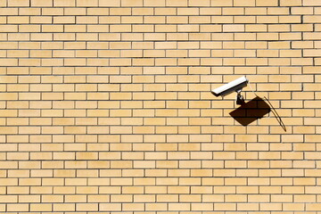 Yellow brick wall with surveillance camera with space for text.