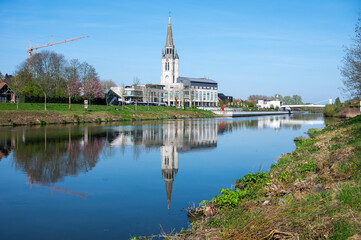 View over the village and Saint Medardus church reflecting in the river Lys or Leie in Wervik, West Flanders, Belgium