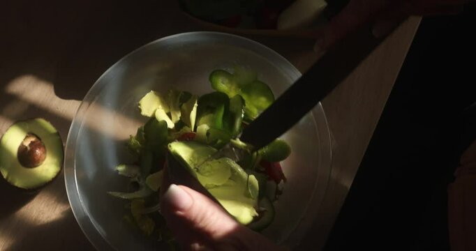 Preparing the salad, cutting the avocado into the clear bowl