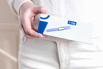 Woman in white clothes holding a pack of Ozempic Insulin injection pen for diabetics and weight loss.