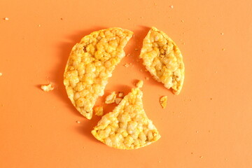There is a broken cornbread loaf lying on an orange background.