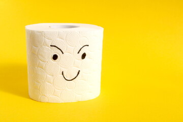 On a yellow background there is a piece of white toilet paper with a face drawn on it.