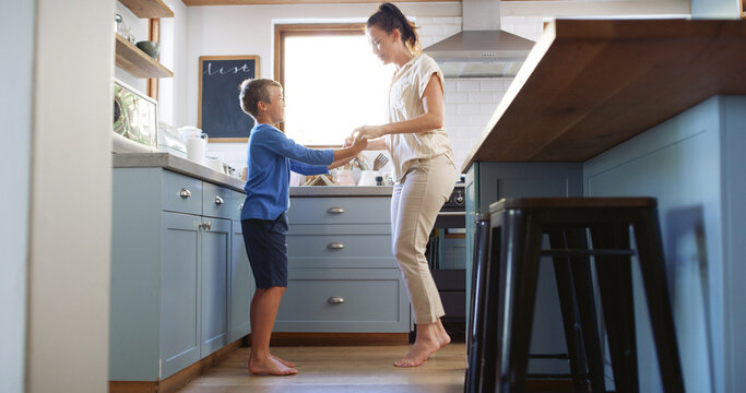 Home, mother and kid dancing in kitchen with holding hands, teaching steps or weekend break. Happy family, woman and boy with music for movement, learning and relationship with love, bonding or trust