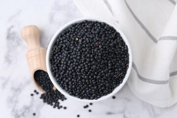 Black lentils on white marble table, flat lay